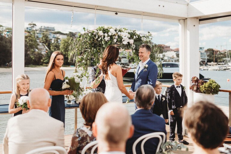 wedding vows of newly married couple with the entourage in the background