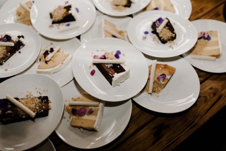 a table set with white plates, each displaying a variety of colorful desserts