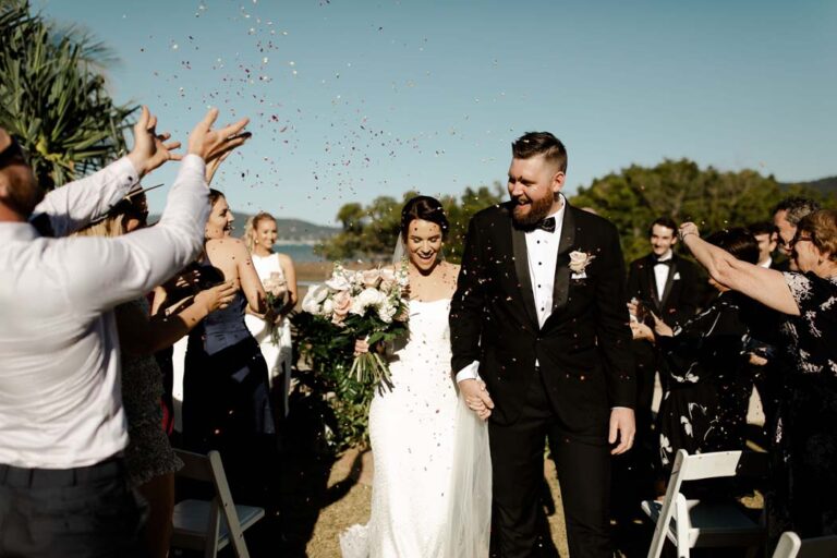 the bride and groom walk joyfully down the aisle, surrounded by colorful confetti falling around them
