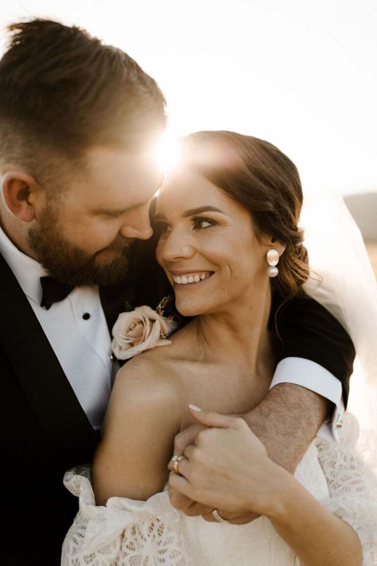 the bride and groom embracing each other at sunset, surrounded by warm colors and a romantic atmosphere