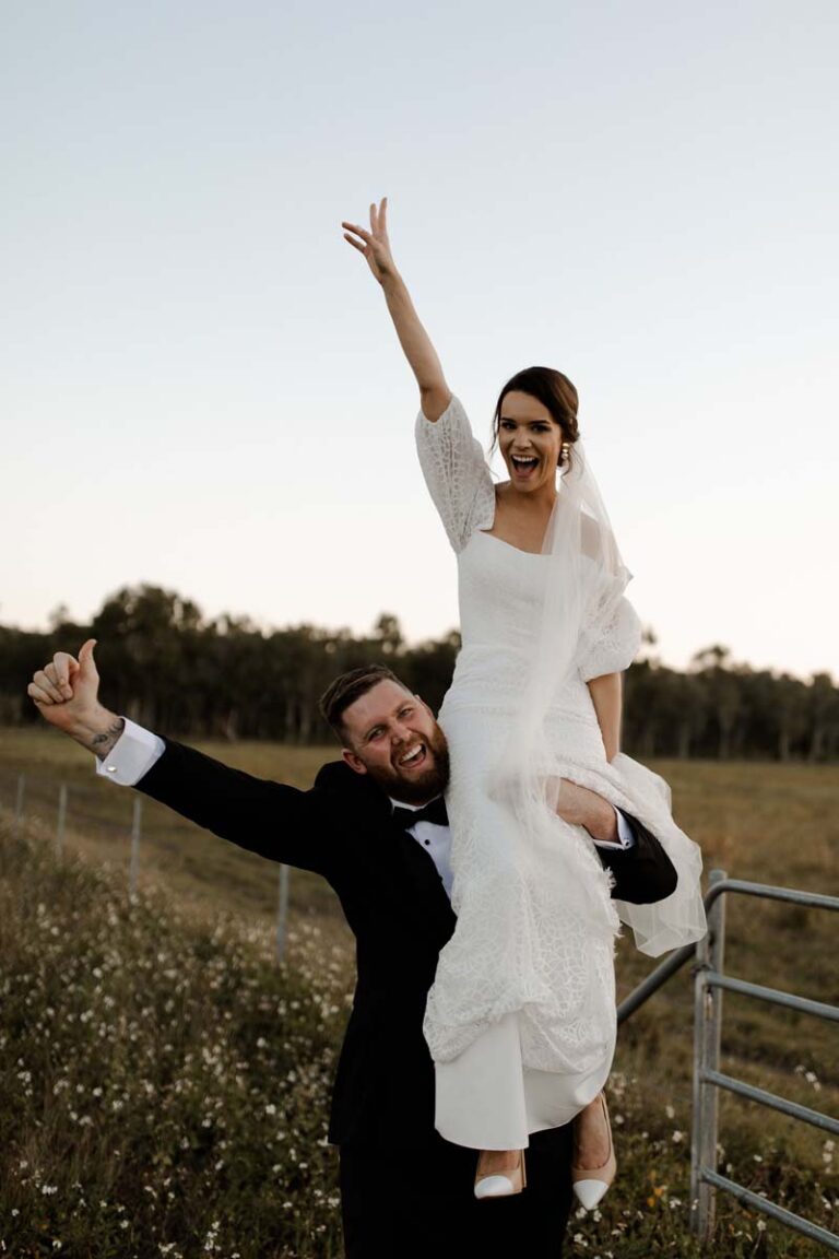 a joyful bride and groom celebrating outdoors with the groom lifting the bride on his shoulder