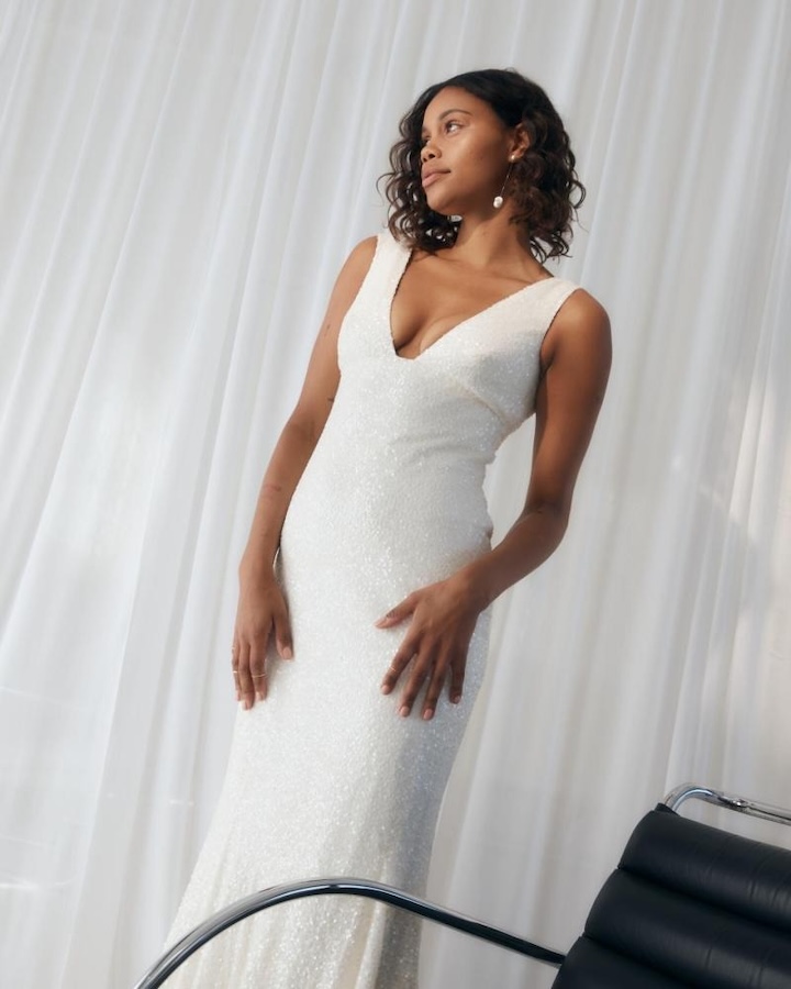 A bride wearing an embellished wedding dress, facing away from the camera