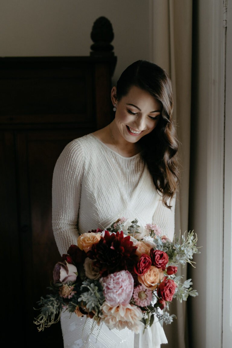 a happy bride smiles brightly while holding a beautiful bouquet of flowers