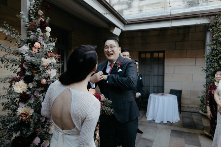 newlywed exchanging vows beside floral arrangements