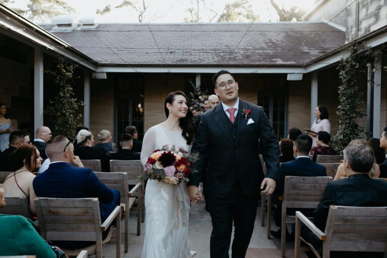 a bride and groom happily walk down the aisle together during their wedding ceremony, surrounded by flowers and guests.