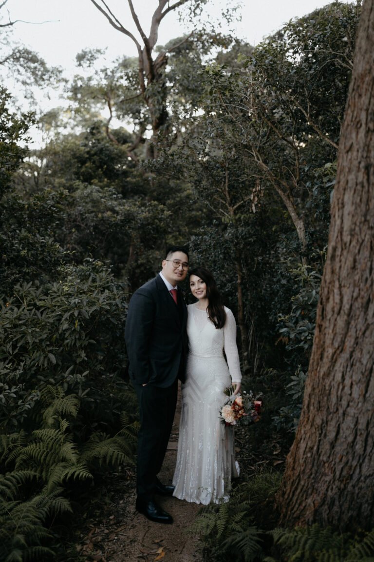 the groom and bride posing in a lush forest setting