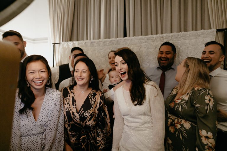 the bride an the wedding guests laughing and smiling together in front of a camera, capturing a joyful moment