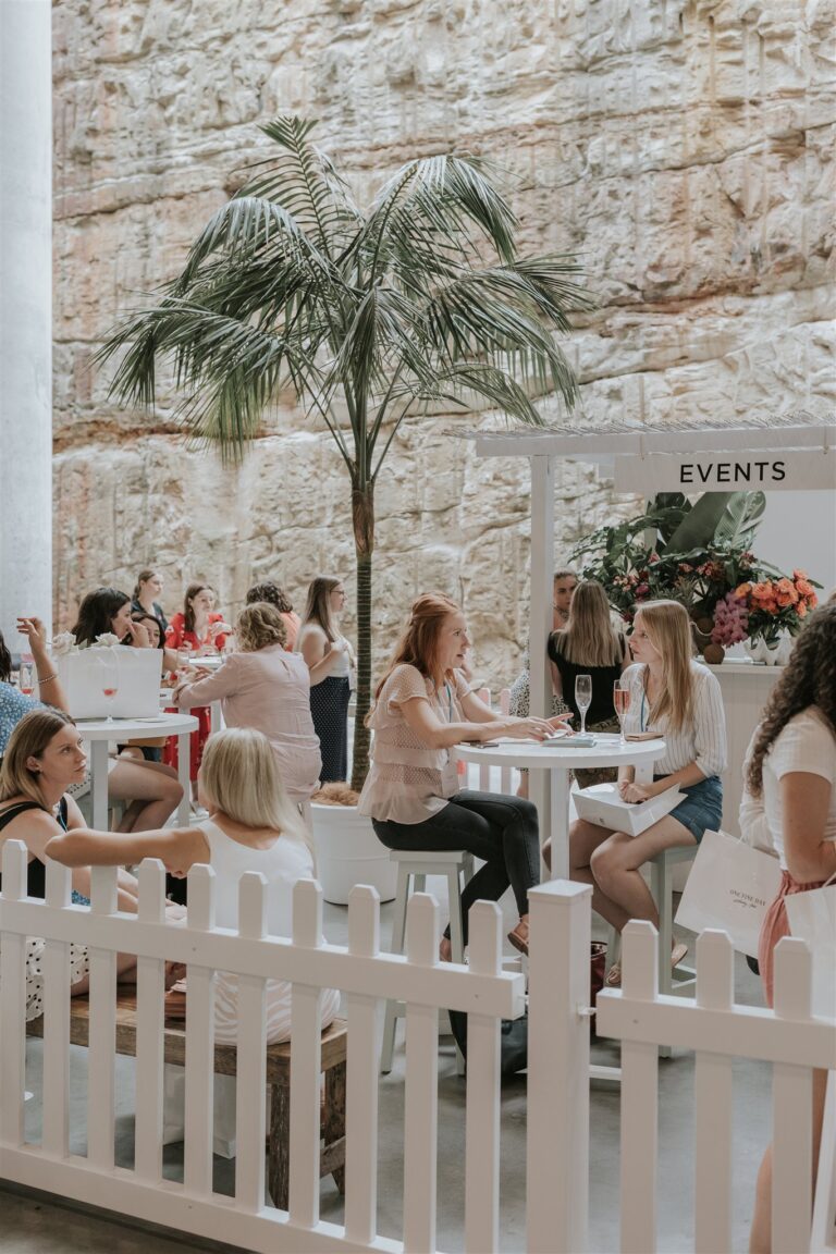 people sitting at tables surrounded, enjoying their time outdoors in a pleasant setting.