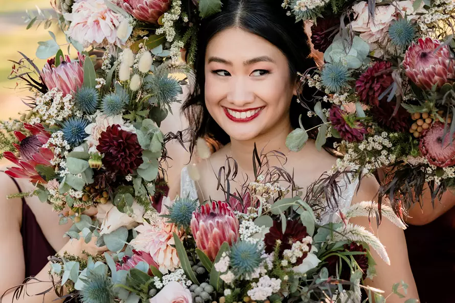 Smiling woman holding a bridal bouquet from Lush Flower Co – one of the best wedding florists in Sydney