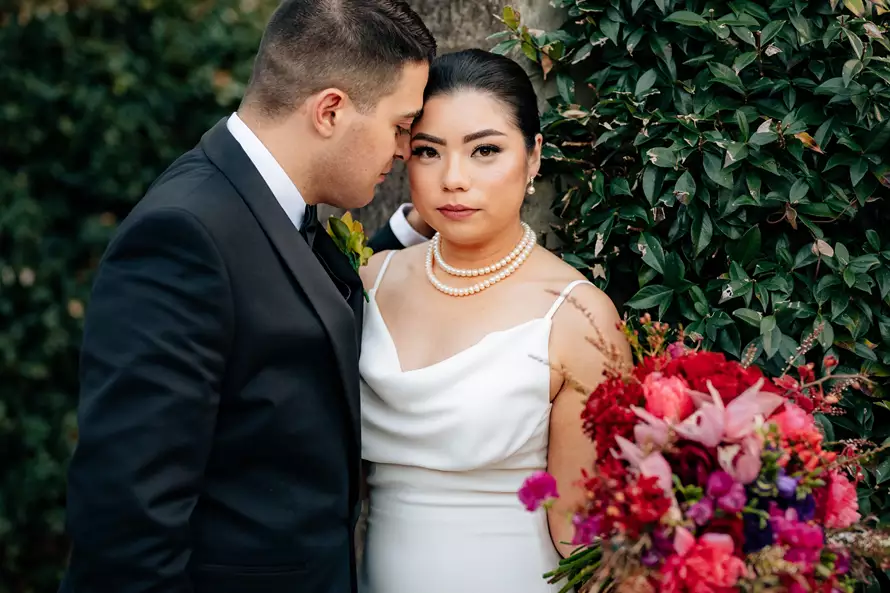 Bride and groom posing with a stunning bouquet from Lush Flower Co – one of the best wedding florists in Sydney.