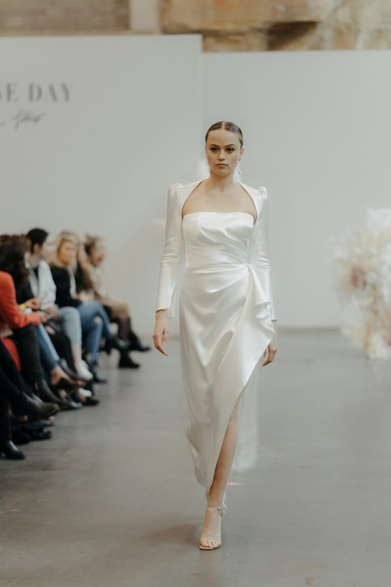 a model walking down the runway wearing a white wedding dress