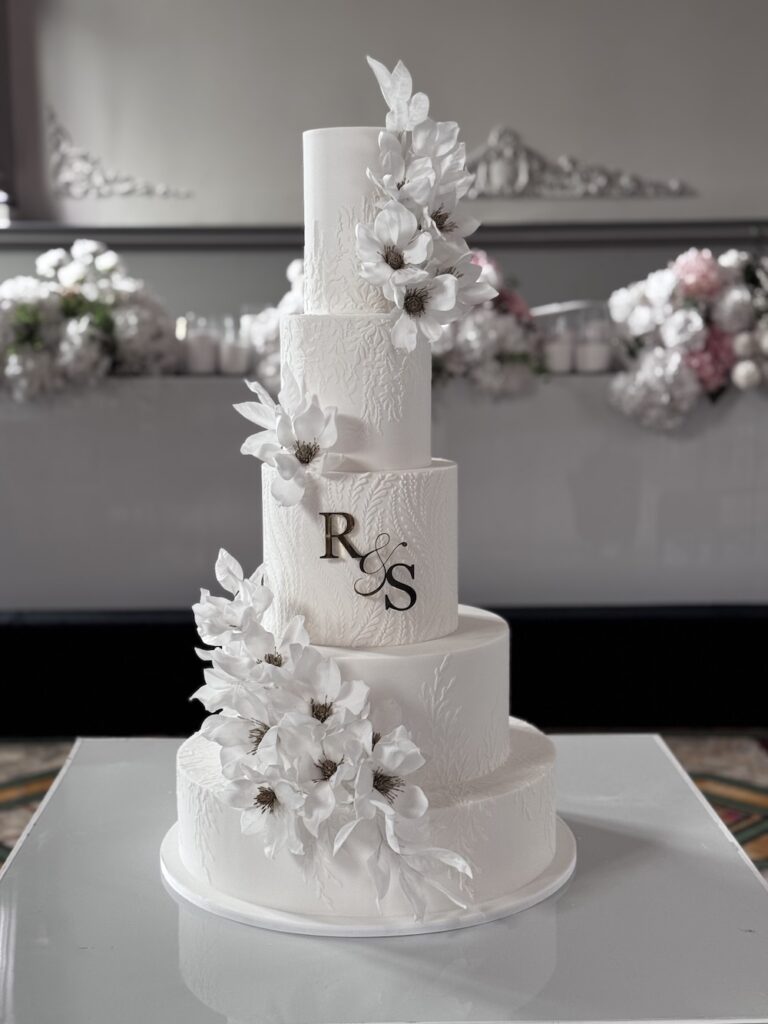 A wedding cake with white wafer flowers wrapped around it, by Sydney cake designer Sunette Fourie