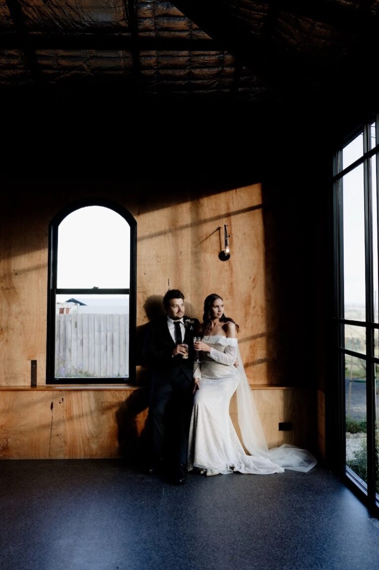 A couple photographed in a room as the sun sets