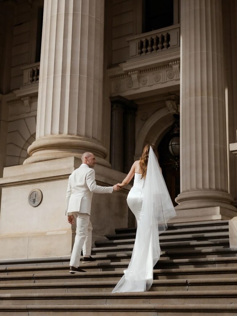 a bride and groom walking up stairs, taken by a melbourne wedding photographer
