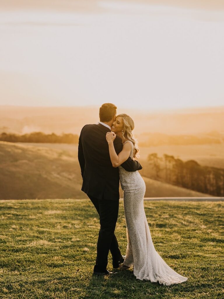 a bridal couple standing in a country field at sunset, taken by a melbourne wedding photographer