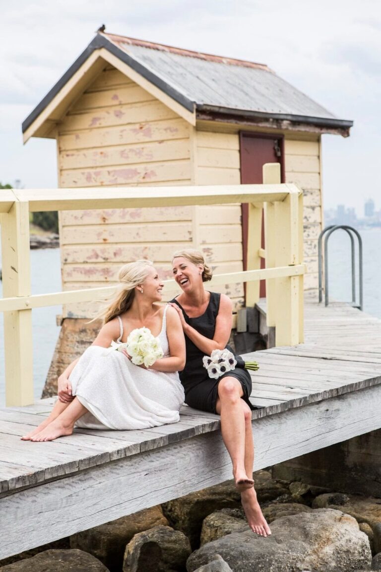 Two women sitting on a pier laughing