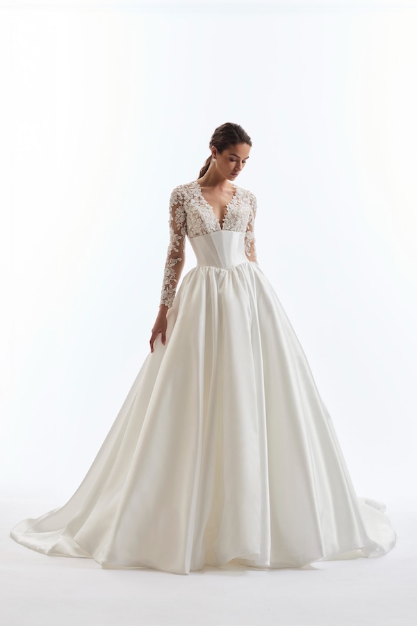 A bride in a regal wedding gown with long sleeves