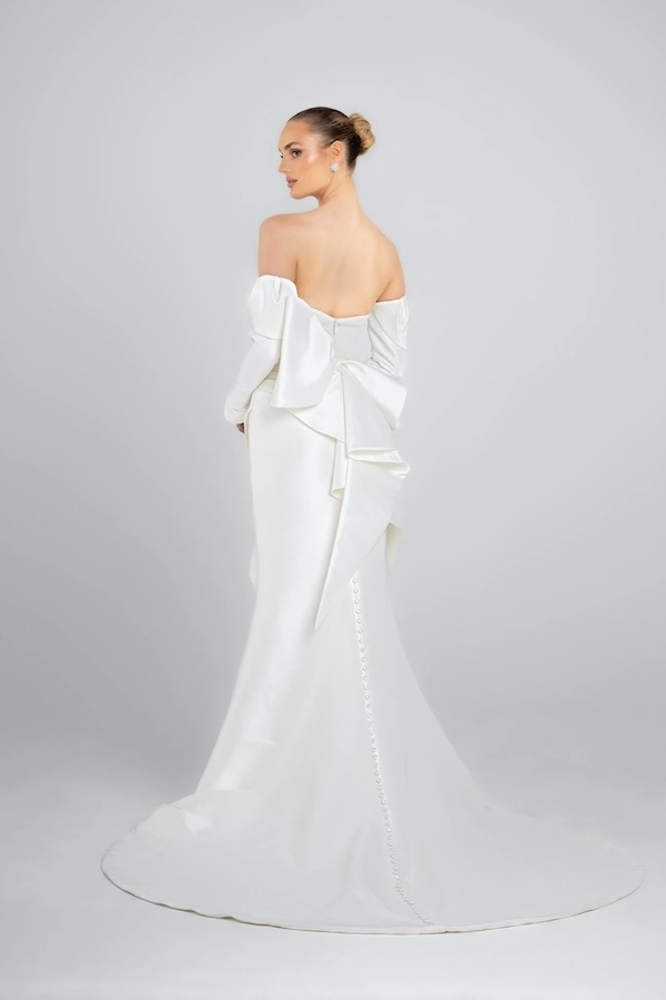 The back of a bride in a long sleeve wedding dress with a bow