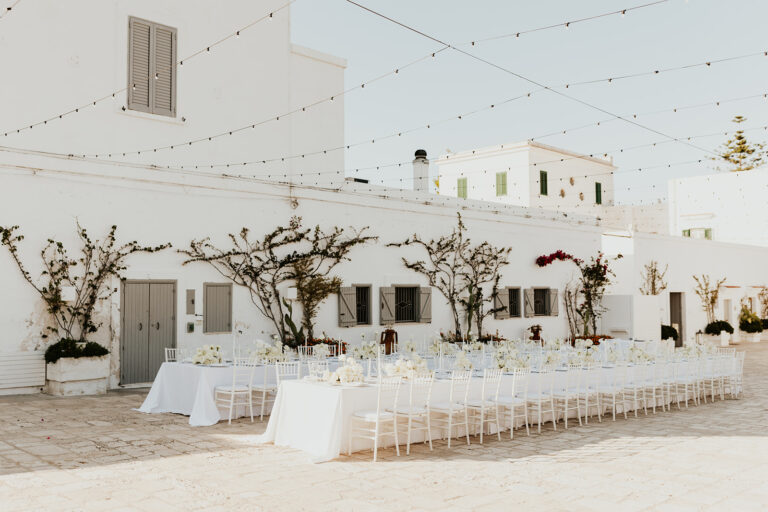 A beautiful outdoor wedding ceremony in a garden with flowers, a decorated arch, and guests in elegant attire.