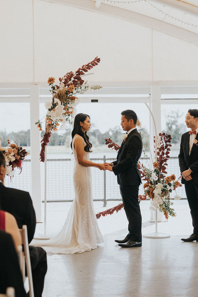 A couple exchanging vows during a wedding ceremony held at Lakeside Pavilion, one of the best wedding venue in Melbourne.