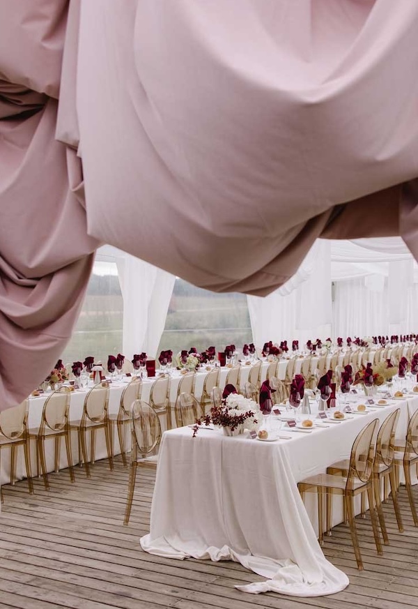 A soft pink canopy over two long tables with gold chairs