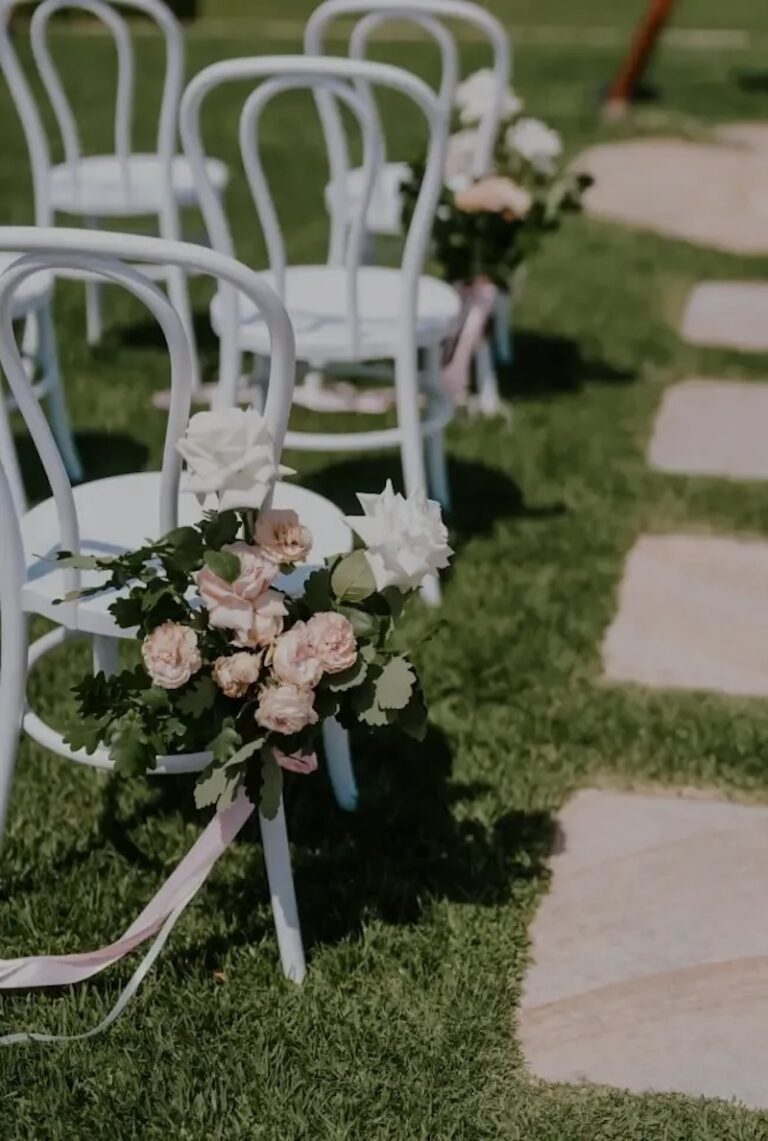 Floral bouquets on white wedding chairs