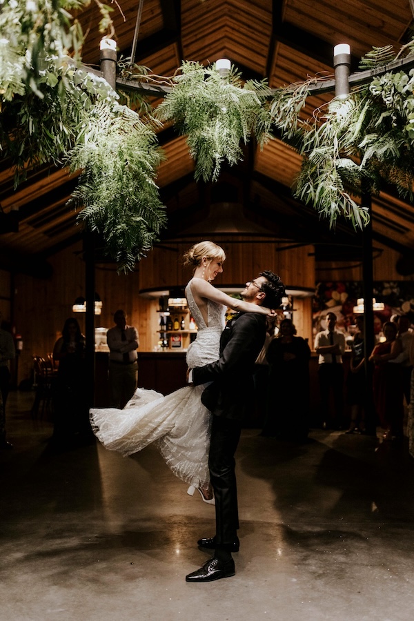 A couple dancing at their wedding under a floral design