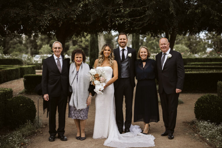 A wedding party smiling for a photo in a garden.