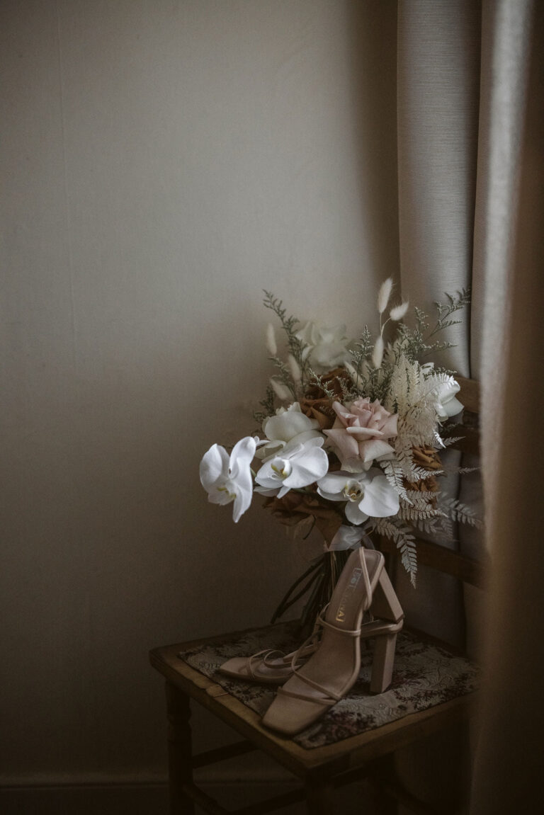 A colorful bouquet of flowers and a pair of shoes placed on a chair.
