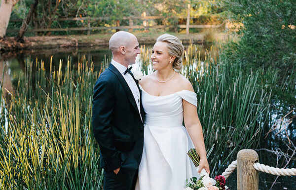 A couple posing in front of a lake.