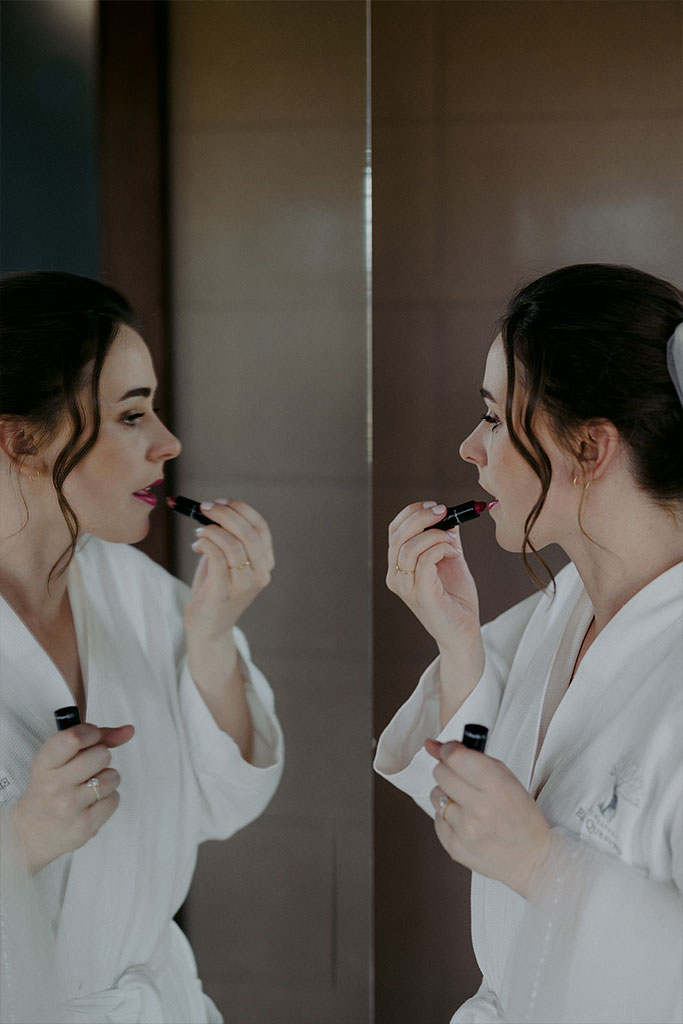 A woman putting lipstick on herself.