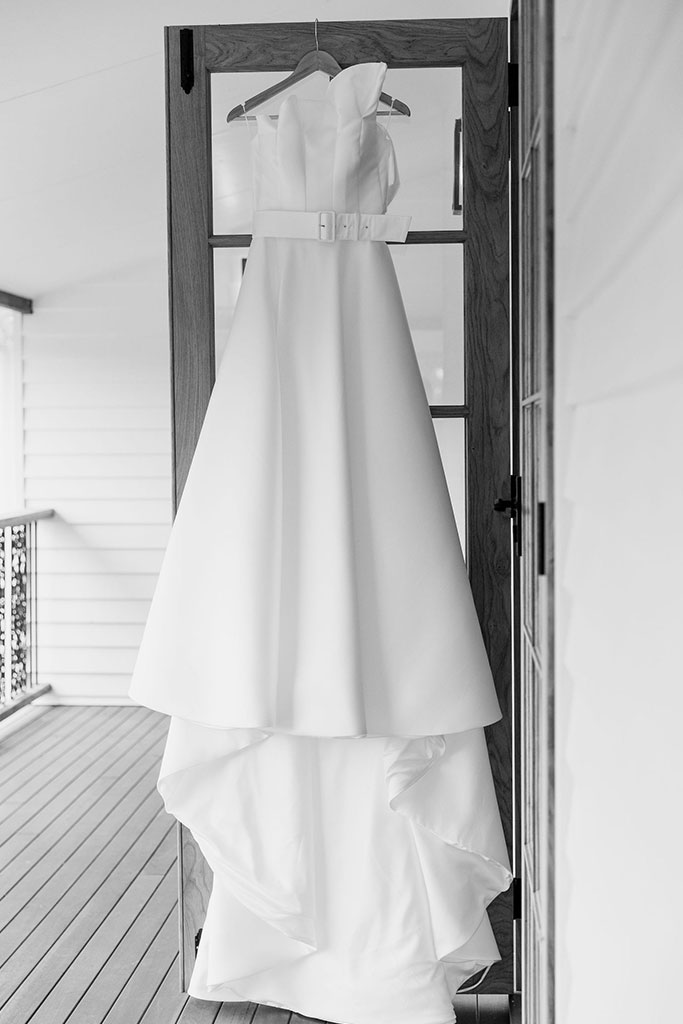 A wedding dress hanging on a door.