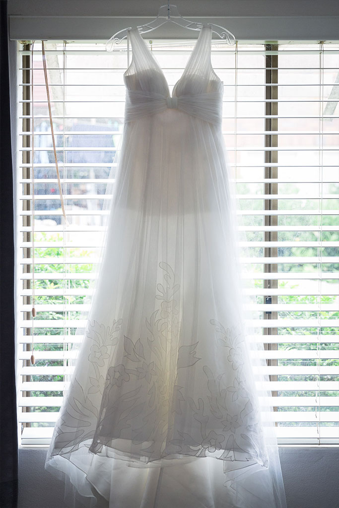 a wedding dress hanging on a window