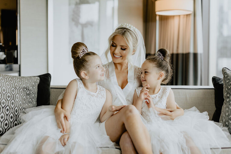 A bride in between two little girls wearing white dresses.