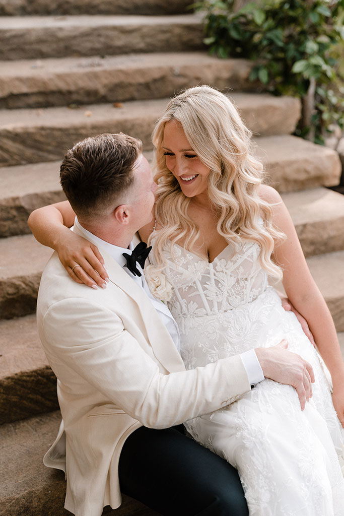 The bride sitting on her grooms lap, looking at him lovingly.