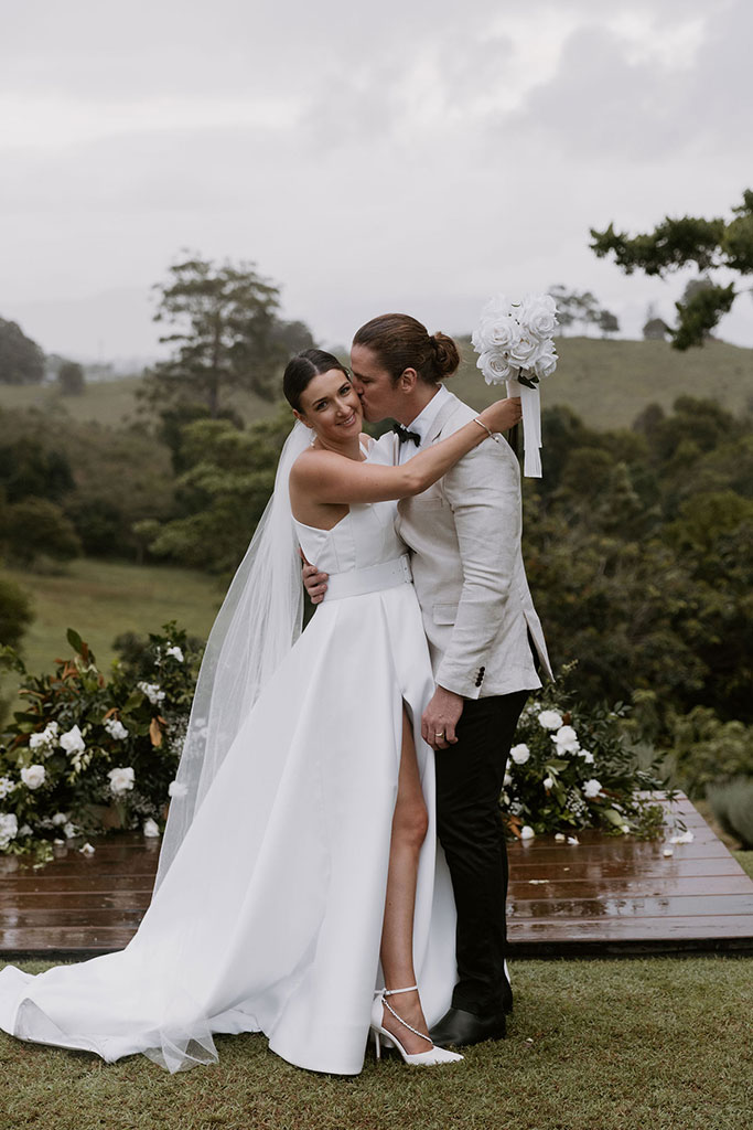 A groom kissing his brides cheeks.