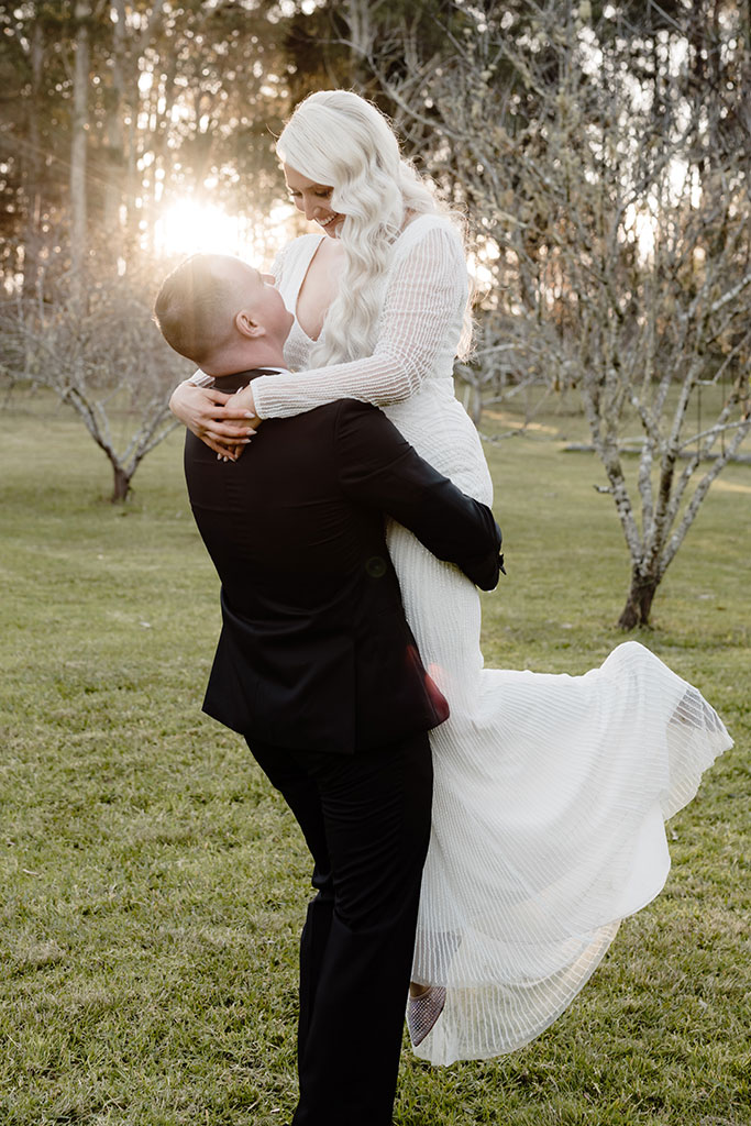 A groom lifting up his bride.