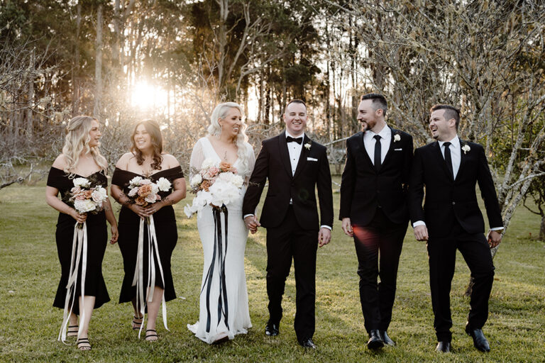 A bride and her bridesmaids, a groom and his groomsmen walking together.