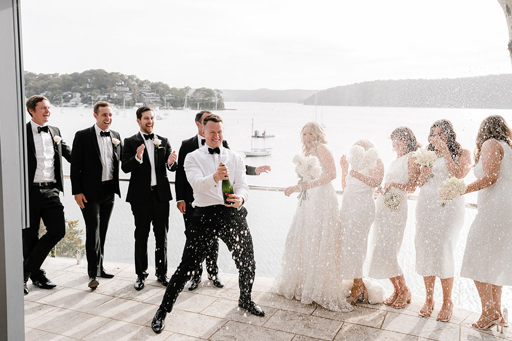 The groom popping a champagne bottle open.