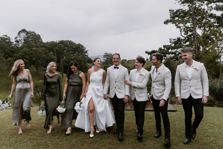 A couple walking with their bridesmaids and groomsmen.