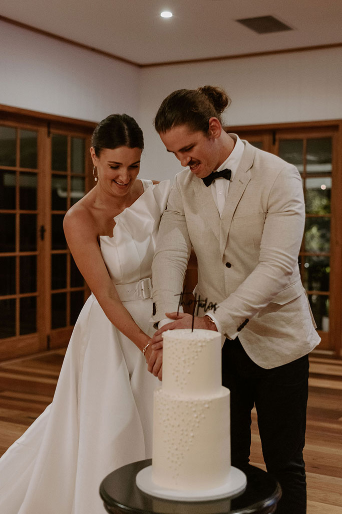 A couple cutting their wedding cake together.
