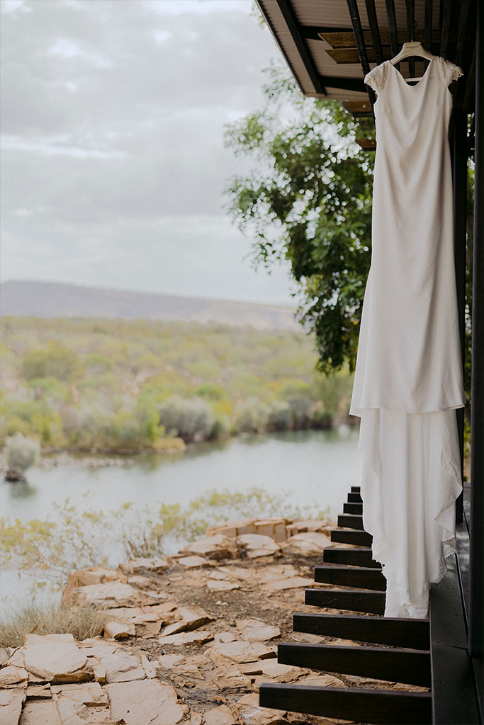 A white wedding dress hanging on a balcony railing, ready for the big day.