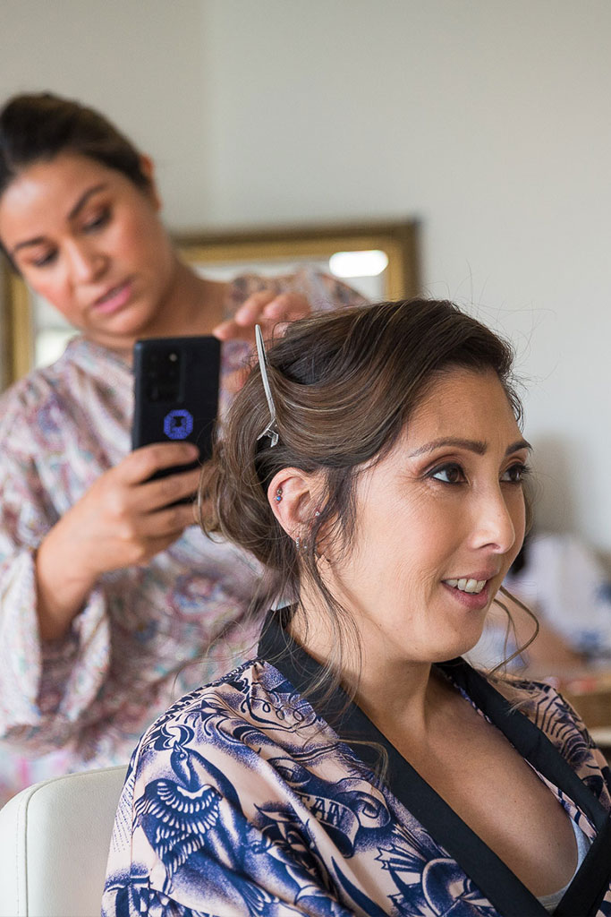 the hairstylist taking a picture of the bride's wedding hair