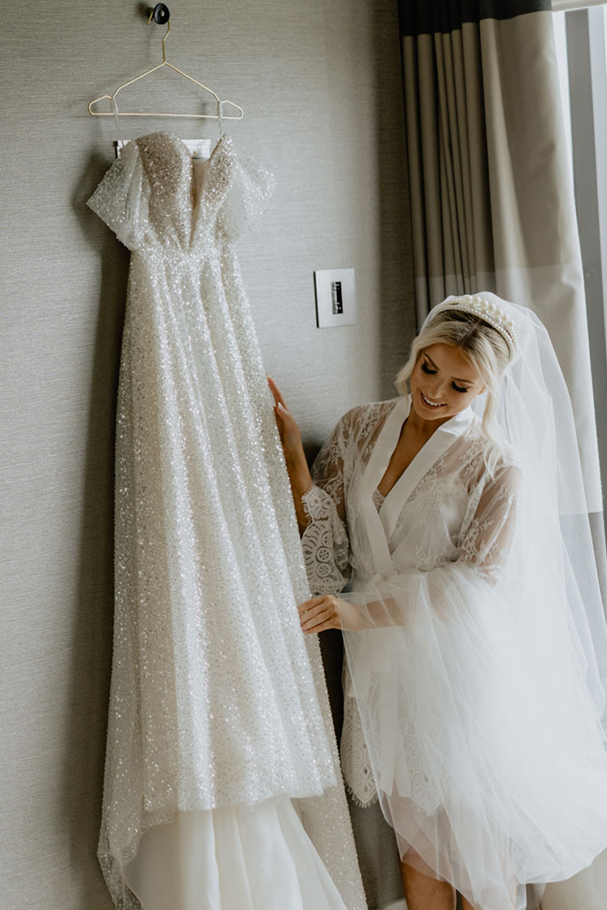 A bride wearing a robe looking at her wedding dress.
