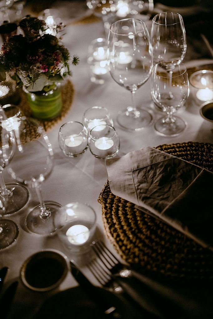 A table set with wine glasses and candles,.