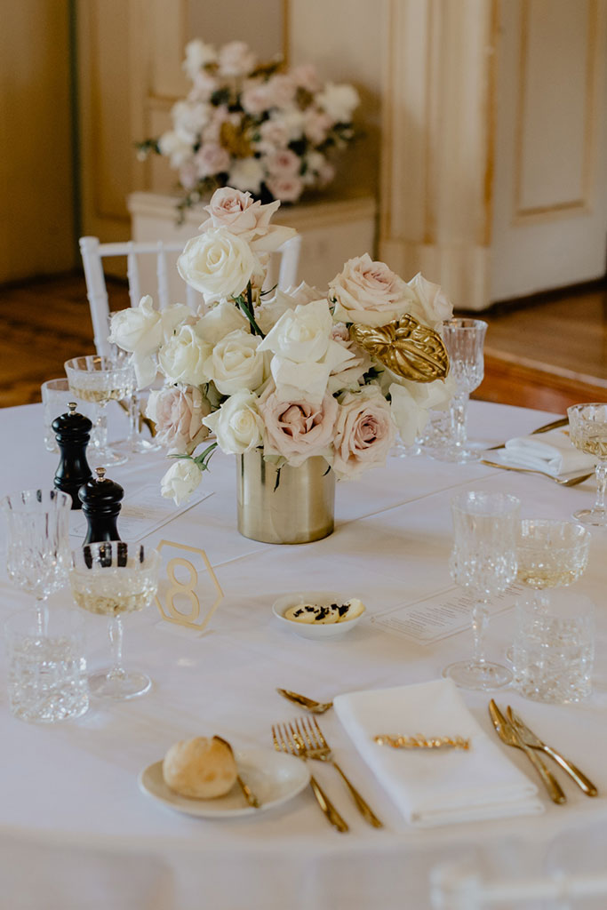 A table with white and gold flowers and place settings.
