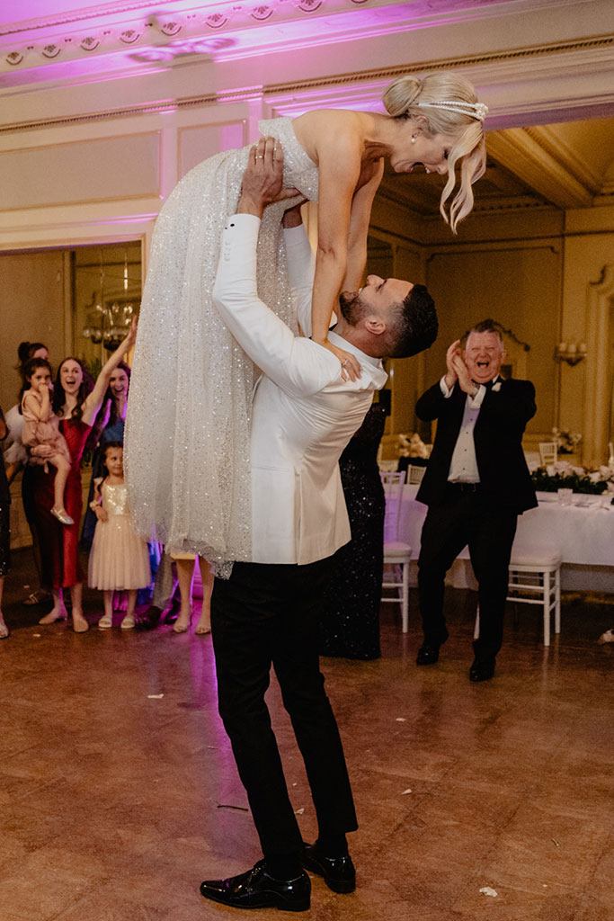 A groom lifting his bride during a dance.