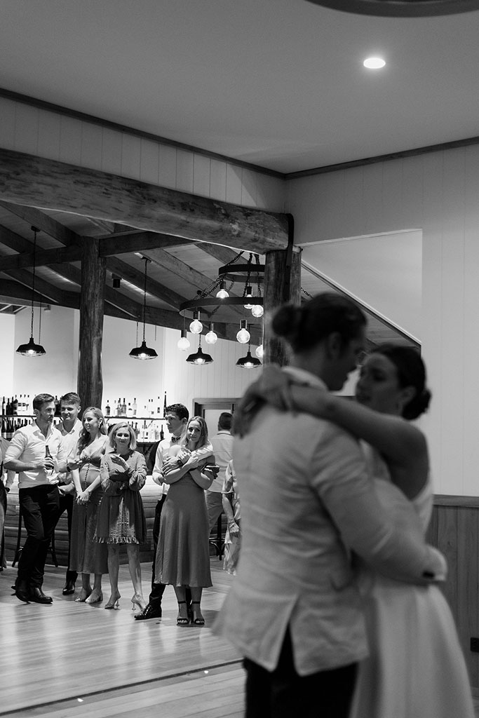People watching as the newly weds dancing slowly, looking at each other lovingly.