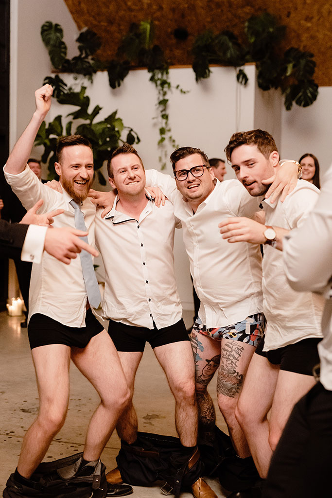 A group of men dancing in their underwear at a wedding celebration.