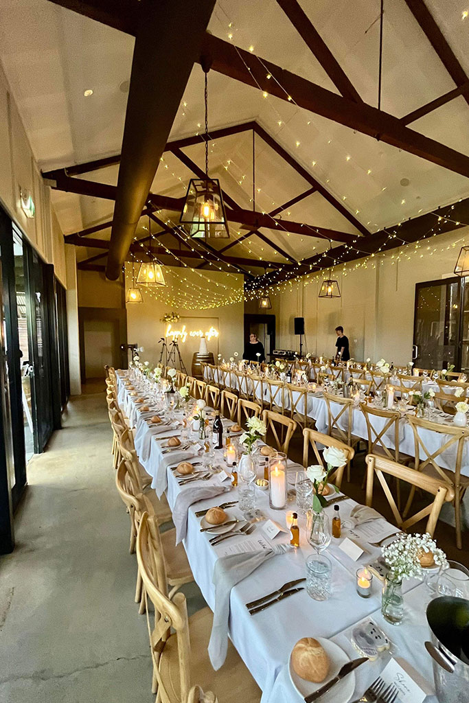 Wedding reception setup with tables and chairs in a spacious room.